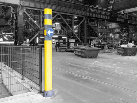 SIGNMARK 150 instalado en un bolardo de seguridad amarillo con rayas negras en una fábrica.